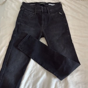 Svarta Replay Hyperflex jeans 28/32 - Säljer ett par svarta Replay Hyperflex jeans i modellen Anbass. Jeansen har klassisk femficksdesign, smal passform och stretchigt material för extra komfort. Snygg tvättad look och diskret Replay-logga vid fickan. Perfekta för dig som gillar stilrena och bekväma jeans. O använda då jag inte ville ha dom för dom inte satt bra sen har dom legat vikta i min garderob och nu vill jag slöja dom för att tjäna lite pengar 