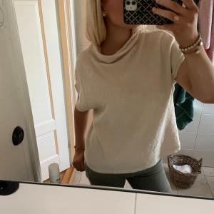 Beige stickad topp från Lindex  - Beige stickad topp från Lindex i storlek. Modellen har korta ärmar, lös passform och en snygg draperad krage. Perfekt att styla med jeans eller kjol för en chill och trendig look.