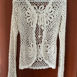 Kofta - Söt vit kofta, löst virkad med små pärlor påsydda. Knytning fram. 