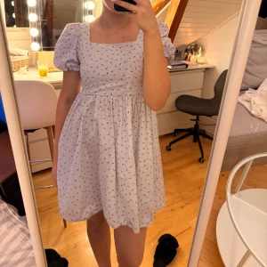 Lila blommig klänning - Lila klänning med vita blommor från Monki i storlek S. 