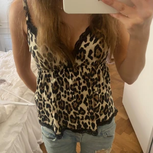 Leopardmönstrad linne med spetsdetaljer - Snygg leopardmönstrad linne med svarta spetsdetaljer längs kanterna grå Gina tricot! Den har smala axelband och en v-ringad design som ger en feminin touch. Den är helt oanvänd med lappen kvar och därför i topp skick!!💗💗💗Köpte för 279 men säljer för 180kr!