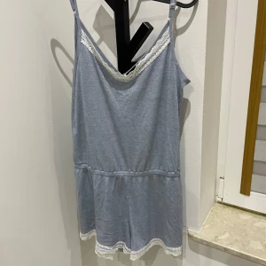 Ljusblå kort piyamas från Even&Odd - Supersöt ljusblå kort piyamas från Even&Odd med smala axelband och v-ringning. Klänningen har vit spetsdetalj vid halsringningen och nederkanten, samt ribbad struktur i tyget. Perfekt för sommarens varma dagar och chill häng. Sitter extremt fint på! NO SIZE