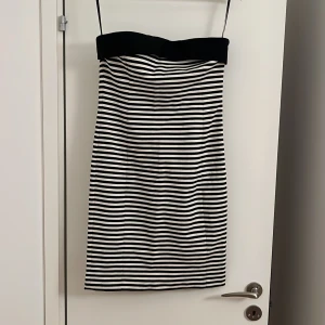 Svartvit randig kort klänning - Snygg kort klänning med smala axelband och svart överdel. Klänningen har ett klassiskt randigt mönster i svart och vitt och är figurnära med rak siluett. Perfekt för dig som gillar stilrena och trendiga plagg med enkel design.  Är en L men passar både s och m också för den är stressig i tyget.