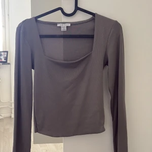 Brun långärmad topp från new yorker - Säljer en stilren brun långärmad topp från Amisu med fyrkantig ringning. Toppen är figurnära och har en enkel, clean design som passar perfekt till jeans eller kjol. Materialet är mjukt och stretchigt för en bekväm känsla.