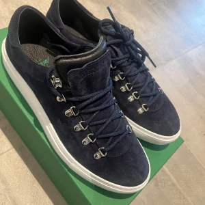 Mörkblå mocka sneakers från Diemme - Snygga mörkblå sneakers från Diemme i mjuk mocka med vit platt sula. Skorna har rund tå, metallhakar för snörning och detaljer i blå skinn på plösen. Perfekt för dig som gillar stilrena och exklusiva sneakers med italiensk känsla.     