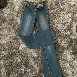 Blå bootcut jeans Denim 1953 Susan - Snygga blå jeans från Denim 1953, modell Susan. Klassisk femficksdesign med bootcut-ben och normalhög midja. Jeansen är i ett mjukt denimtyg med lätt slitningar och har gylf med dragkedja och knapp. Säjs för att dem inte kommer till användning!💖