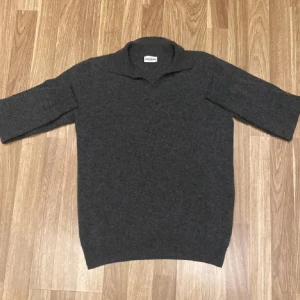 Mörkgrå polotröja John Henric - Snygg mörkgrå polotröja från John Henric i storlek S. Det är en kashmir ull blandning, vilket gör den supermjuk och skön. Den har en klassisk krage och trekvartsärm, perfekt för dig som gillar stilrena och tidlösa plagg.