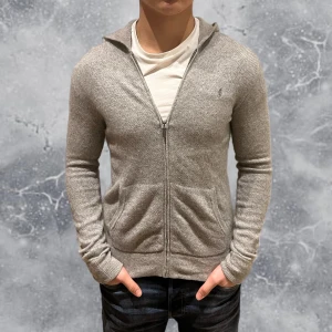 Ralph Lauren cashmere Zip Hoodie grå - •Ralph Lauren full-zip hoodie grå. 30% cashmere & 70% cotton. Skick: 8/10, Inga skador! Storlek: 14/16 ungdom = XS~. Sitter bra på modellen på bild! Modell: 173 cm, 63 kg. Authentic: ✅. Hör av dig vid frågor eller funderingar.