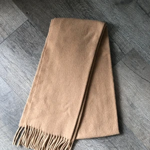 Beige halsduk i ull från Filippa K - Klassisk beige halsduk från Filippa K i mjuk ull. Stilren design med fransar i ändarna, perfekt att slänga över axlarna för en clean och snygg look. Passar till det mesta och är superenkel att matcha med både jacka och kappa. Köpt på Åhlens! 