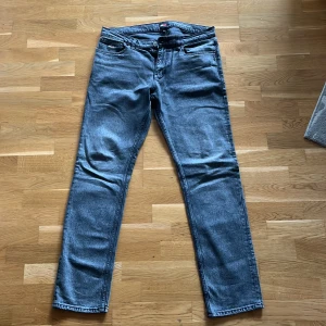 Grå jeans från Tommy Jeans - Snygga grå jeans från Tommy Jeans med klassisk femficksdesign och broderad logga på bakfickan. Jeansen har regulator fit passform och raka ben, tillverkade i mjukt denimtyg. Storlek 32x34. Köpta för 1000 kronor på rea, original pris 1200. Använda 5 gånger, har endast legat i garderoben resten av tiden, köpt för 4 månader sen. Säljer på grund av att dem inte passar mig längre och gillade aldrig dem men hoppas någon annan kan njuta av dem. Priset kan pratas!