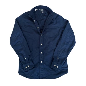 Mörkblå skjorta från Selected Homme - Snygg mörkblå oxfordskjorta från Selected Homme i ekologisk bomull. Skjortan har klassisk krage, vita knappar och en bröstficka. Regular fit med långa ärmar och stilren look som funkar till jeans eller chinos. De står storlek xs men den är som en s