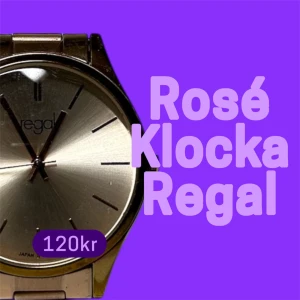 Roséguldfärgad klocka från Regal - Stilren klocka från Regal i roséguld med metallarmband och minimalistisk urtavla. Klockan har en rund form och enkla indexmarkeringar utan siffror, vilket ger en clean och modern look. Perfekt accessoar för dig som gillar en klassisk men trendig stil.