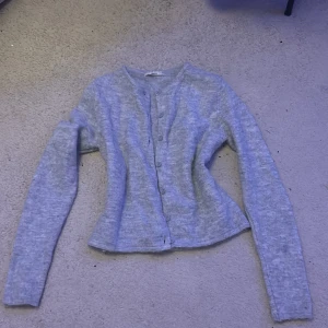 Ljusgrå kofta från Gina Tricot - Supersöt ljusgrå kofta från Gina Tricot i mjukt stickat material.  Den här rund hals och knappar framtill. Perfekt att slänga över en topp eller bära som den är. Långärmad och riktigt skön att ha på sig under kyliga dagar.