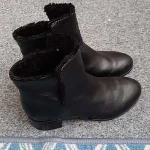 Svarta boots från & Other Stories - Säljer ett par svarta boots från & Other Stories med rund tå och låg klack. Utsidan är i skinn och insidan är fodrad med mjuk päls för extra värme. Perfekt för dig som gillar stilrena och bekväma skor med en clean look. Skor används bara några gånger  och köps för 1250 kr.