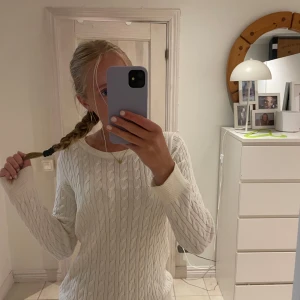 Vit tröja BASIC U - Snygg vit kabelstickad tröja från BASIC U i storlek S. Tröjan har rund hals och ribbade muddar. Materialet är mjukt och skönt.