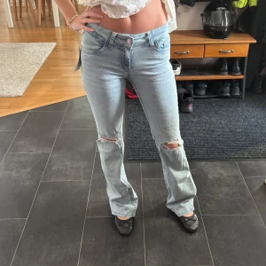Bootcut ljusblå jeans med slitningar - Säljer ett par super snygga och trendiga byxor från Nelly i storlek 34 som är helt oanvända och endast testade!💞💞