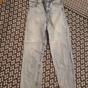 Ljusblå jeans från Perfect Jeans - Säljer ett par ljusblå jeans från Perfect Jeans med klassisk femficksdesign och raka ben. Jeansen har hög midja och är tillverkade i mjukt denimtyg. Baktill finns två stora fickor och fram knäppning med dragkedja och knapp. Perfekt för dig som gillar enkel och clean stil.