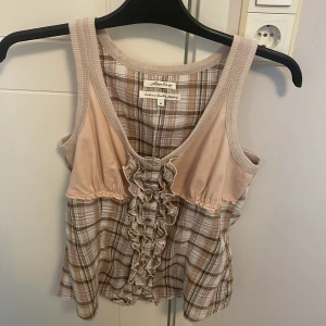 Sommmartopp - Säljer en söt topp från Replay med rutigt mönster i beige och rosa toner. Toppen har volangdetaljer framtill och är i mycket bra skick💞