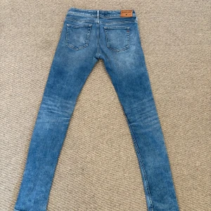 Blå jeans från Replay - Snygga blå jeans från Replay med en klassisk femficksdesign och knappgylf. Perfekta för en avslappnad stil. Märkeslogga på bakfickan ger en extra touch.