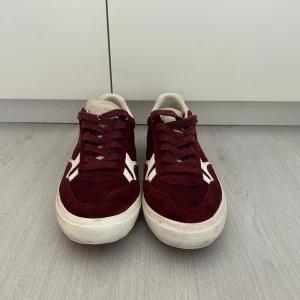 Vinröda sneakers från Pepe Jeans - Snygga vinröda sneakers från Pepe Jeans med vita detaljer och snörning. Skorna är jättesparsamt använda och är i jättebra skick. Det sitter några småstenar i sulan som lätt går att plocka bort annars är skorna perfekta. Storlek 43 och sitter true to size. Hör av dig vid frågor! 