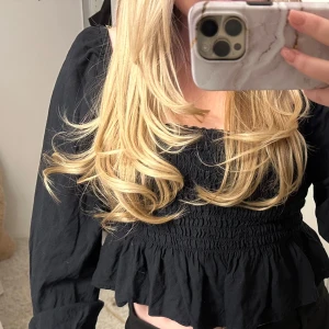 Svart långärmad topp från Bik Bok - Säljer en svart långärmad topp från Bik Bok i storlek XS. Toppen har en smockad design med volangdetaljer vid nederkanten. Perfekt för en stilren look.