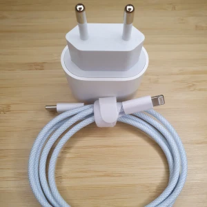 Vit laddare med flätad kabel, XTW Lightning Quick Charging Set, 30W Charger and 33W 1m Lightning Cable - Säljer en vit laddare med en flätad kabel. Laddaren har en USB-C-port och kabeln har en USB-C till Lightning-kontakt. Perfekt för snabb och säker laddning av dina enheter. Kabeln är ljusblå och vit, vilket ger ett stilrent intryck.