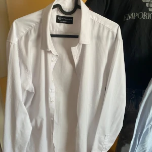 Vit skjorta från Riley - Klassisk vit skjorta från Riley i storlek L. Perfekt för en stilren look med knappar framtill och en traditionell krage. Passar bra till både jeans och kostymbyxor. 299 styck pris alla för 699kr.