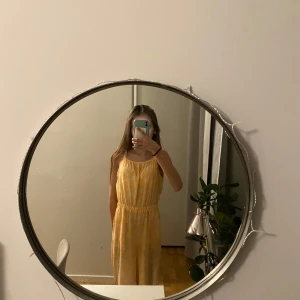 Gul blommig klänning med byxor från H&M - Säljer en söt gul jumpsuit från H&M med vita blommor. Den har smala axelband och en elastisk midja för en bekväm passform. Perfekt för soliga dagar! 🌼super fin och är i bra skick. Inga fläckar. Inga hål. 