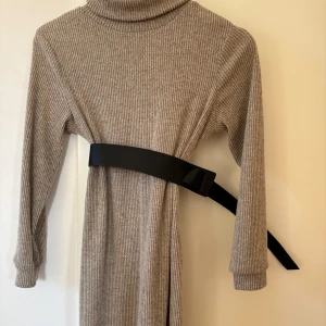 Beige brun  ribbad klänning med bälte från SHEIN - Snygg beige brun ribbad klänning med långa ärmar och ett svart bälte i midjan. Perfekt för en stilren look. Klänningen har en hög krage och är gjord i ett mjukt material.