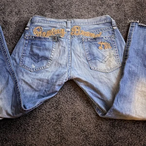 Blå jeans med broderad text - Tjena! Säljer dessa otroligt snygga jeans med tryck på rumpan, ass snygga! Säljer pga att det inte är min stil! Obs priset är inte hugget i sten! 