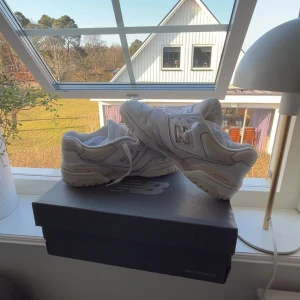 Vita sneakers från New Balance - Säljer ett par vita sneakers från New Balance. Skorna har en klassisk design med snörning och en bekväm passform. Perfekta för vardagsbruk och stilrena nog att matcha med det mesta.