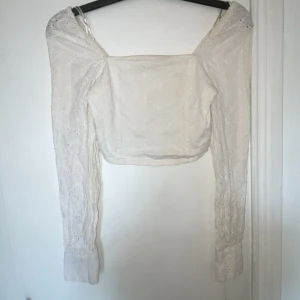 Vit blus från Bik Bok - Säljer en söt vit blus från Bik Bok med broderade detaljer. Blusen har långa ärmar och en offshoulder-design som ger en romantisk look. Perfekt för vårens och sommarens tillfällen.