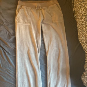 Beige mjukisbyxor från Juicy Couture - Säljer ett par bekväma beige mjukisbyxor från Juicy Couture. Byxorna har en loose passform med snörning i midjan och praktiska fickor både fram och bak. Perfekta för en avslappnad stil.