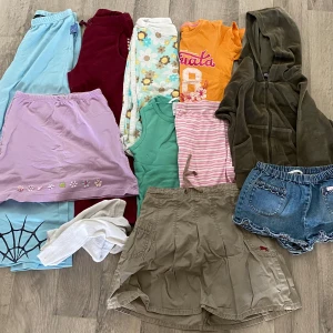 Klädpaket stl. 110/116!  - Superfint paket i stl 110/116! Helt och rent klädpaket men i använt skick. Innehåll: En lila kjol. Ett par jeansshorts. Ett par mjuka, sköna blå byxor med spiderman tryck. Mjuka, gosiga vinröda fleecebyxor. Trekvart byxor med blommor. Rosa/vitrandiga trekvart byxor. Vita strumpbyxor. Mörkgrön, gosig hoodie med dragkedja i materialet velour. Grönt linne. Orange T-shirt med tryck. Beige kjol. 