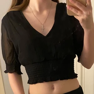 Svart croppad blus från Bubbleroom - Säljer en svart croppad blus från Bubbleroom med v-ringning och korta ärmar. Blusen har en matchande kjol som jag också säljer om man är intresserad kan man kolla på kjolen i min profil med. Settet är använt 1 gång och har Inge defekter.
