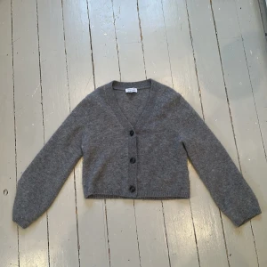 Grå jätte snygg stickad kofta från & other stories ❤️❤️❤️ - Säljer en mysig grå stickad kofta från  & other stories . Koftan är croppad med en v-ringad design och har tre knappar framtill. Perfekt för lager-på-lager under kyligare dagar. Knappt använd 💯❤️