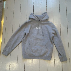 Grå hoodie från Butter Goods ❤️ - Säljer en stilren grå hoodie från Butter Goods med vit text på bröstet. Den har en klassisk känguruficka och justerbar huva. Perfekt för en avslappnad look. Godisen är knappt använd och en jättemysig hoodie som passar alla i stilen 💕🌸Hoddien är lite oversize men det är så snyggt 🍒🫰🏻