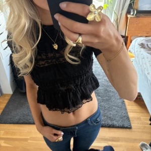 Svart spetsblus - Snygg svart blus med spetsdetaljer och volanger. Den är croppad och har korta ärmar. Aldrig använd