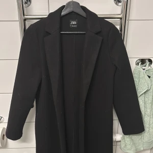 Svart kappa från Zara - Snygg svart kappa från Zara med klassisk design. Perfekt för både höst och vår. Den har långa ärmar och en stilren look som passar till många olika outfits. Ett måste i garderoben för den stilmedvetna!