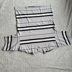 Randig t-shirt från H&M - Säljer en randig t-shirt från H&M i oversized fit. T-shirten har svarta och vita ränder på en ljusgrå bas. Perfekt för en avslappnad stil.