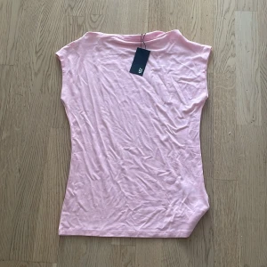 Ny Rosa ärmlös topp från 157 - Säljer en söt rosa ärmlös topp från 157. Perfekt för varma dagar eller som ett lager under en jacka. Toppen har en enkel och stilren design.