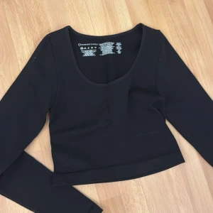 Svart långärmad topp  - Snygg svart långärmad topp från med en djup v-ringning. Perfekt för en stilren look. Toppen är i ett mjukt och stretchigt material som ger en bekväm passform.