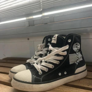 Svarta Isabel Marant sneakers high-top - Coola high-top sneakers från Isabel Marant i svart canvas med vita detaljer och snörning. Skorna har vit gummitå och sula, samt grafiskt tryck på sidan. St 37