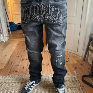Gråa baggy jeans med tryck - Kan passa folk som inte har storlek large jag är 180 dom passar bra. .Säljer ett par gråa jeans med baggy passform och coolt stort tryck framtill. Jeansen har slitna detaljer, broderad logga på sidan och klassiska bakfickor. Perfekta för dig som gillar streetwear och vill sticka ut.