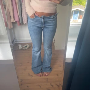 Ljusblå bootcut jeans med låg midja - Säljer ett par ljusblå jeans med bootcut och låg midja. Jeansen har klassisk femficksdesign, dragkedja och knapp framtill. De är tillverkade i mjukt denimtyg och har en snygg utsvängd passform nertill. Perfekta för en avslappnad och trendig look.