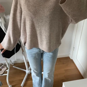 Beige stickad tröja med loose fit - Mysig beige stickad tröja med loose passform och långa ärmar. Tröjan har en enkel design utan mönster och är perfekt för dig som gillar en chill och avslappnad stil. Materialet är mjukt och känns skönt mot huden, perfekt att slänga på sig när det är lite kyligt ute.