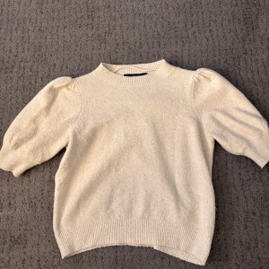 Beige stickad tröja  - Superfin beige stickad tröja från Vero Moda med puffiga korta ärmar och ribbade muddar. Säljer då den tyvärr inte kommer till användning längre
