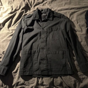 Overshirt från Marc O'Polo - Stilren overshirt från Marc O'Polo med klassisk krage, tre stora fickor framtill och knäppning med svarta knappar. Skjortan är tillverkad i bomull och har en avslappnad passform som passar perfekt till lager-på-lager-stil.