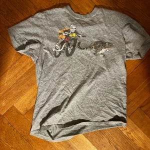 Paul and smith tshirt - Säljer en Paul and Smith t-shirt med coolt tryck av en mumie på motorcykel som jagas av en leopard. 