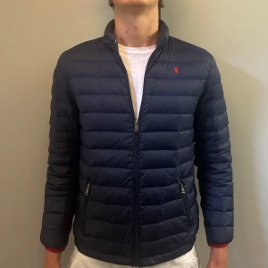 RALPH LAUREN JACKA - Fet marinblå Ralph Lauren jacka i barnstorlek XL, sitter som XS/S. Mycket bra skick förutom liten defekt på ryggen som knappt syns (se bild). Nypris 3000, skriv för fler funderingar!